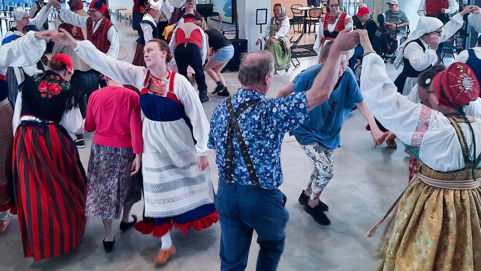 Kansallispukutuuletus Kuopion museolla, tanhutansseja, eli kansallispukuun pukeutuneita tanhuajia ja tanssiin osallistuvaa yleisöä